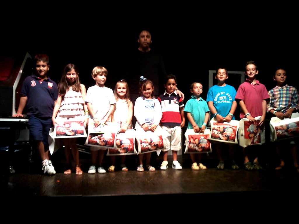 Niños sobre el escenario durante actividad de magia.